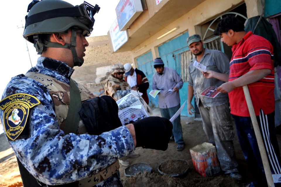 US Navy 081206-N-1810F-259 An Iraqi National Policeman hands out leaflets to Iraqi civilians during a walking patrol through the Rashid community in Bahgdad