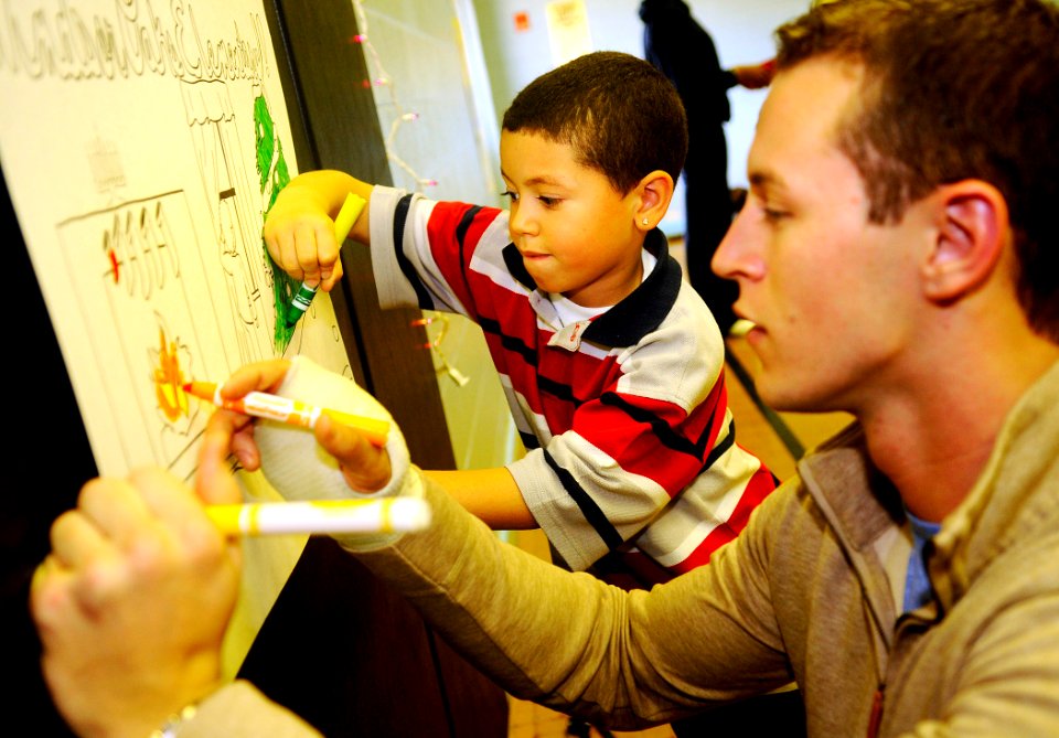 US Navy 081210-N-5345W-018 Aviation Electronics Technician 3rd Class Ryan Forde colors a holiday poster alongside his mentee