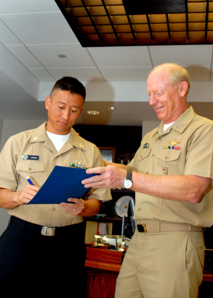 US Navy 081219-N-5476H-010 Navy Counselor 1st Class Matthew Johnson signs his reenlistment papers during a reenlistment ceremony conducted by Adm. Robert F. Willard