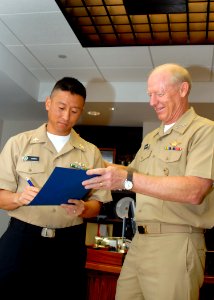 US Navy 081219-N-5476H-010 Navy Counselor 1st Class Matthew Johnson signs his reenlistment papers during a reenlistment ceremony conducted by Adm. Robert F. Willard
