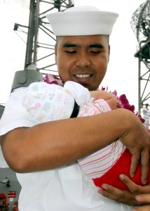 US Navy 081219-N-9758L-125 Electrician's Mate 1st Class Rafael Martinez greets his newborn child during the return of USS Reuben James (FFG 57) at Naval Station Pearl Harbor