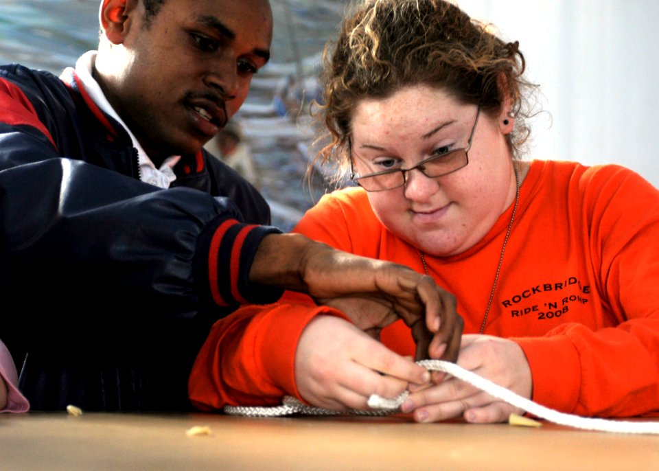 US Navy 081212-N-1831S-118 Boatswain's Mate 2nd Class Jamie Marriott helps a student from the LifeSkills Learning Center tie a square knot