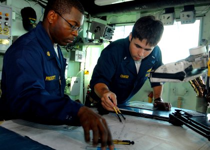 US Navy 081223-N-9134V-022 Chief Quartermaster Melvin Prescott, left, and Lt. j.g. Jeremy Chayer plot a navigation course aboard the amphibious dock landing ship USS Carter Hall (LSD 50)