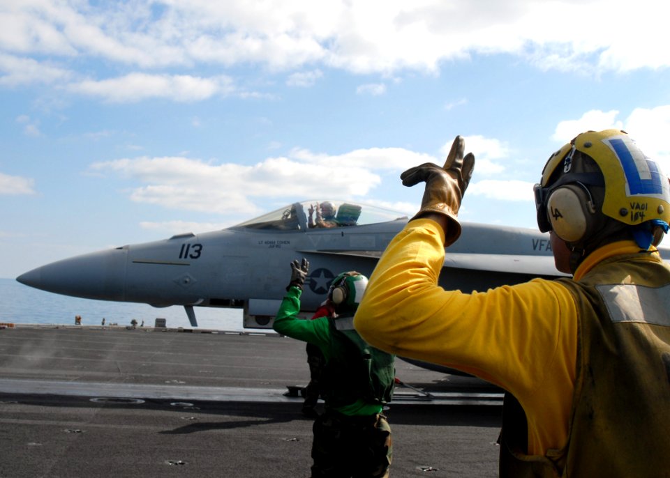 US Navy 081229-N-9900B-003 Aviation Boatswain's Mate (Handling) 3rd Class Antonio Rodriguez spots an F-A-18 Super Hornet assigned to the