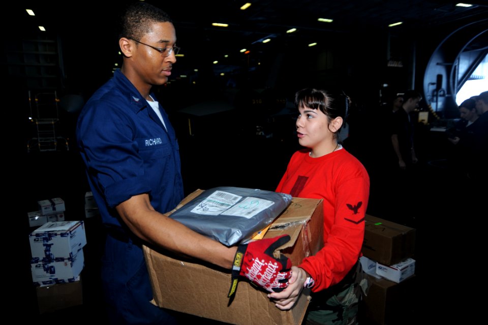 US Navy 090104-N-2908M-004 Postal Clerk 3rd Class Justin Richard gives mail to Aviation Ordnanceman 3rd Class Ivianna Ortiz during mail call
