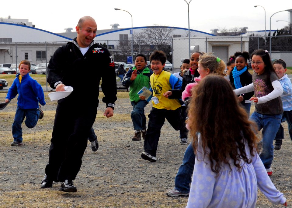 US Navy 090107-N-2013O-024 Quartermaster 2nd Class Aaron Martinez, assigned to the Arleigh-Burke class guided-missile destroyer USS The Sullivans (DDG 68), runs from students during a game of tag at The Sullivans Elementary Sch