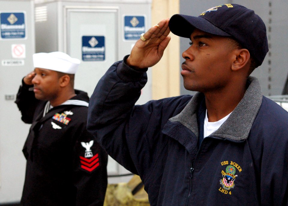 US Navy 090109-N-6410J-032 Electronics Technician 3rd Class Kelly O'Neal and Culinary Specialist 1st Class Everett Lloyd salute the ship's ensign during pre-deployment morning colors
