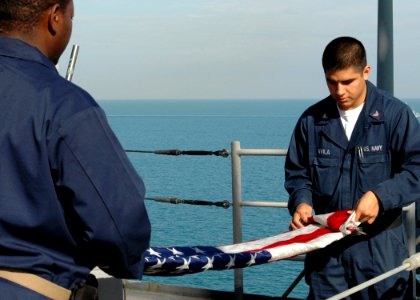 US Navy 090112-N-9134V-082 Chief Quartermaster Melvin Prescott and Quartermaster 3rd Class Perry Avila fold the national ensign