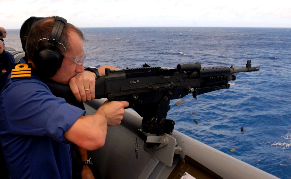US Navy 090119-N-1688B-363 British Cmdr. Mark Fitzsimmons, director of staff for Africa Partnership Station (APS) 2009, fires the M-240 machine gun while aboard the amphibious transport dock ship USS Nashville (LPD 13)