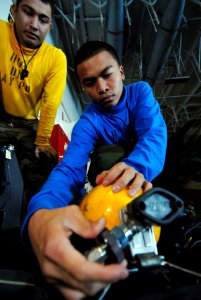 US Navy 090116-N-3946H-032 Aviation Boatswain's Mate 3rd Class Michael Melgar supervises Aviation Boatswain's Mate Airman Apprentice Enrico Rabina through the process of removing a self-contained breathing apparatus (SCBA) bott