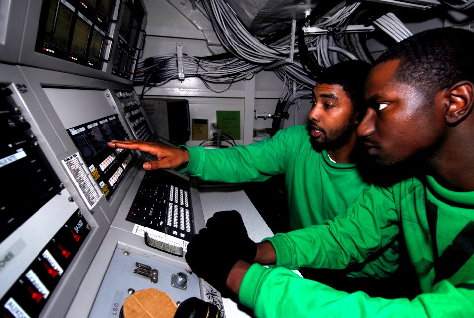 US Navy 090121-N-9610C-030 Interior Communications Electrician 3rd Class John Cummings, left, from Augusta, Ga., trains Interior Communications Electrician 3rd Class Joshua Aziz, from Los Angeles, to operate the visual landing