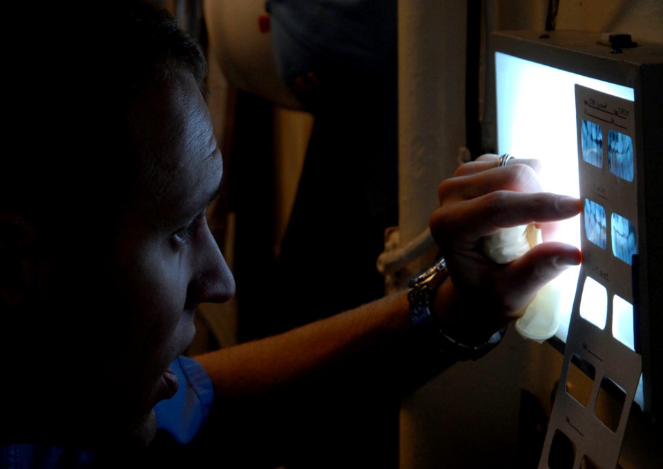 US Navy 090119-N-1688B-025 Lt. Joseph Nencka, amphibious transport dock ship USS Nashville (LPD 13) dental officer, reviews dental X-rays while examining a patient