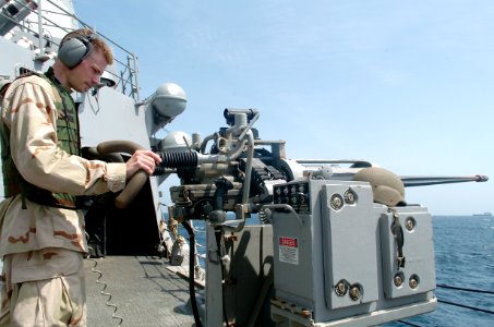 US Navy 090125-N-3931M-146 Information Systems Technician 3rd Class Adam Gayner mans a 25MM chain gun aboard the guided-missile destroyer USS Mason (DDG 87) while monitoring a small boat transiting from the merchant vessel MV F photo