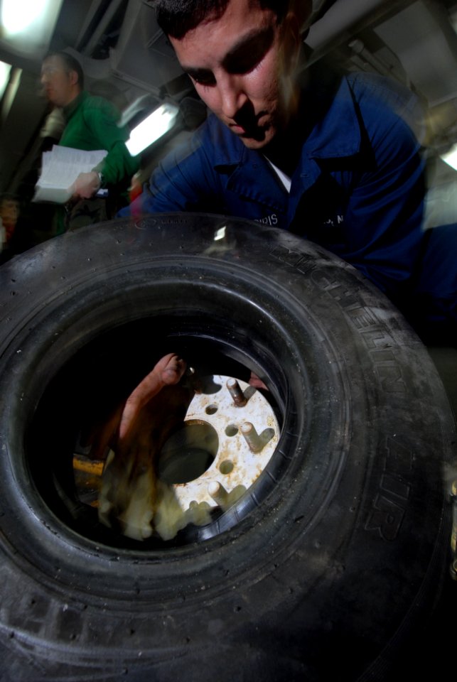US Navy 090123-N-3946H-026 Aviation Support Equipment Technician Airman Joseph Zaliagiris changes the tire of an aircraft spotting dolly