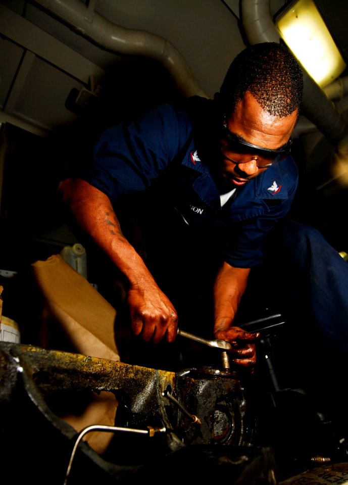 US Navy 090121-N-6538W-020 Aviation Support Equipment Technician 3rd Class Eric Steverson tightens a bolt on the steering column of a forklift