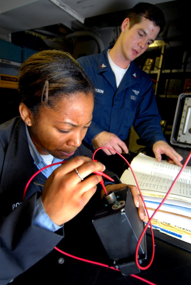 US Navy 090123-N-3946H-037 Aviation Electrician's Mate 3rd Class Andrew Jackson, right, helps Airman Apprentice Christina Porter troubleshoot a fuel probe control panel to an F-A-18 Hornet