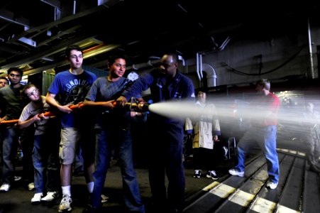 US Navy 110730-N-ZZ999-010 Damage Controlman 1st Class Charles Patterson shows tiger cruise participants how to use a fire hose in the well deck ab