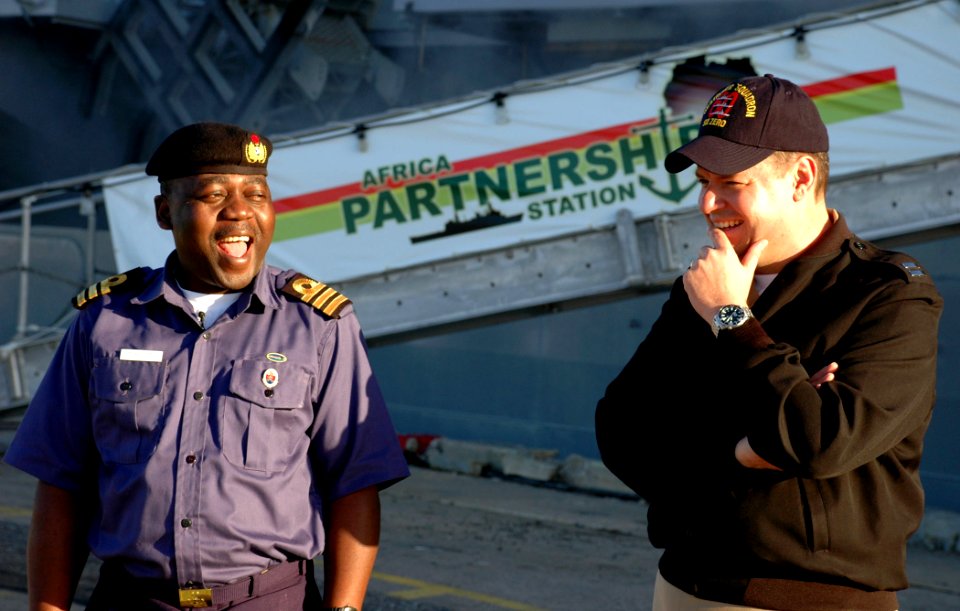 US Navy 090128-N-1655H-001 Nigerian Navy Cmdr. Enoch Bello, left, and Lt. Doug High laugh in front of the amphibious transport dock ship USS Nashville (LPD 13) during a port visit by Nashville to Rota, Spain