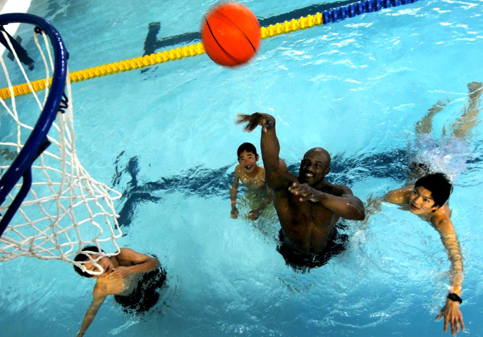 US Navy 090124-N-0807W-201 Yeoman 2nd Class Akaiya Miller, from Claxton, Ga., plays basketball with Japanese children from the Omura Kodomo Children's Home at a pool party during a community relations project