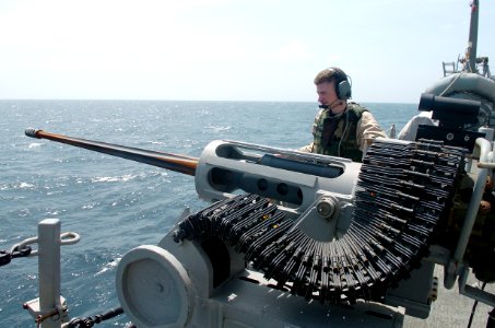 US Navy 090125-N-3931M-124 Information Systems Technician 3rd Class Adam Gayner mans a 25MM chain gun aboard the guided-missile destroyer USS Mason (DDG 87) while monitoring a small boat transiting from the merchant vessel MV F