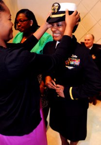 US Navy 090129-N-7526R-172 Ensign Judy Reid smiles as her cousin Veronica Thomas places her cover, signifying the transition from enlisted to officer