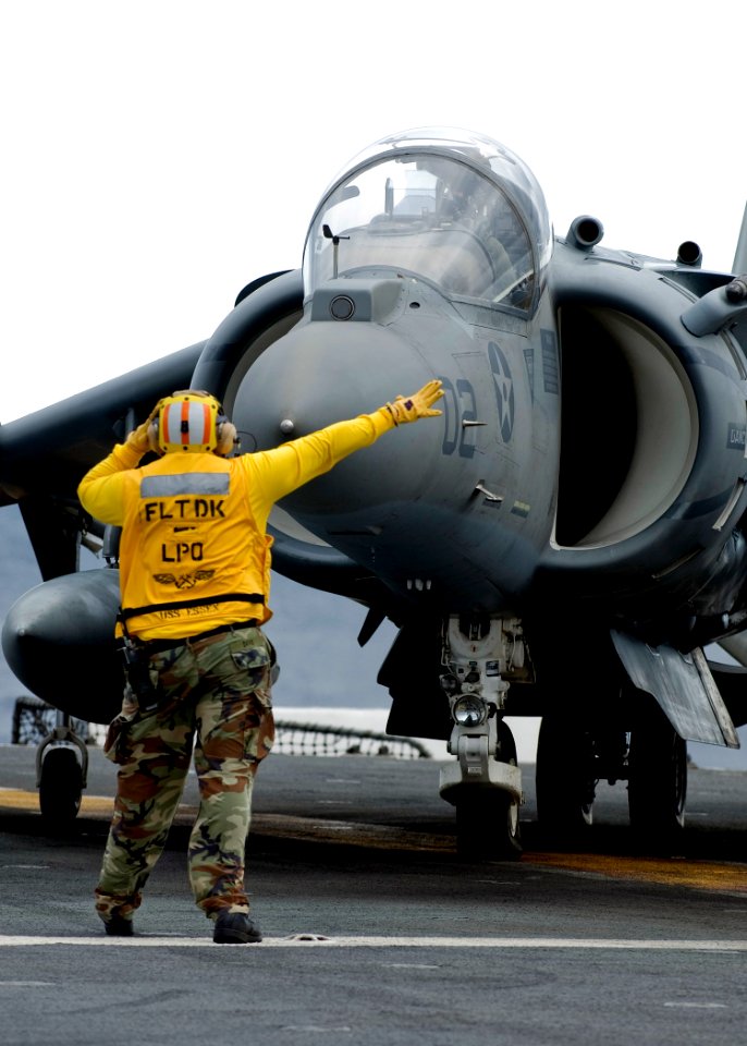 US Navy 090130-N-5253W-001 Aviation Boatswain's Mate (Handling) 1st Class Darrio Davis, from Baltimore, directs the pilot of an AV-8B Harrier II aircraft