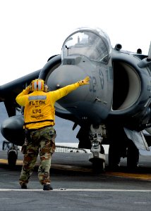 US Navy 090130-N-5253W-001 Aviation Boatswain's Mate (Handling) 1st Class Darrio Davis, from Baltimore, directs the pilot of an AV-8B Harrier II aircraft