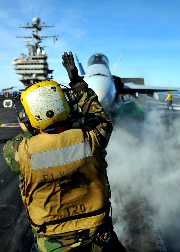 US Navy 090204-N-7981E-227 Aviation Boatswain's Mate (Handling) 3rd Class Bart Kooym guides an F-A-18C Hornet onto the No. 2 catapult on the flight deck of USS Abraham Lincoln (CVN 72)