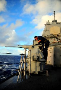 US Navy 090129-N-4774B-007 Gunner's Mate 2nd Class Nicholas Brassard performs maintenance on the MK-38 25mm machine gun system