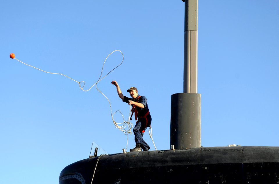 US Navy 090204-N-8467N-006 Electronics Technician 3rd Class Chuck Youngberg throws a line from the fast-attack submarine USS Pittsburgh (SSN 720) to the pier to haul up the shore phone cable aboard