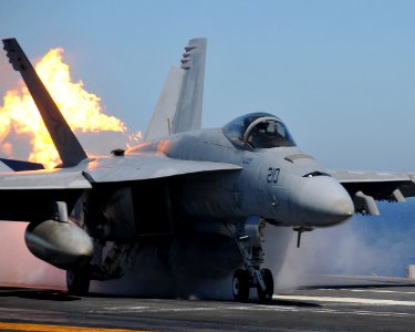US Navy 090202-N-7981E-138 An F-A-18E Super Hornet belts fire as it launches from USS Abraham Lincoln (CVN 72) photo