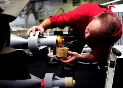 US Navy 090205-N-8822R-048 Aviation Ordnanceman 3rd Class Matthew Squires checks for scratches or debris on the seeker head of a GBU-12 Paveway II laser-guided bomb