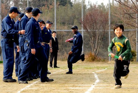 US Navy 090207-N-8546L-666 Personnel Specialist 2nd Class Michael Graham races toward his relay team during a race against children from the Myojoo-en Children's Home