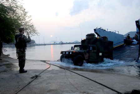 US Navy 090207-N-6936D-026 Seaman Matthew Atkinson directs vehicles as they arrive by landing craft in Sattahip, Thailand photo