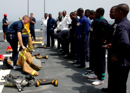 US Navy 090213-N-1655H-002 Africa Partnership Station embarked trainees observe crew members aboard the amphibious transport dock ship USS Nashville (LPD 13) demonstrate the proper donning of a firefighting ensemble during dama