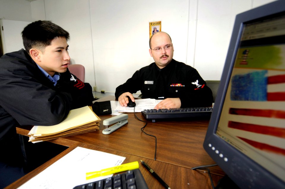 US Navy 090210-N-8534H-002 Volunteer income tax assistance (VITA) member Boatswain's Mate 1st Class William Burch, left, looks on as Culinary Specialist 3rd Class Eteinne Mendizabal prepares his 2008 Federal and State Taxes