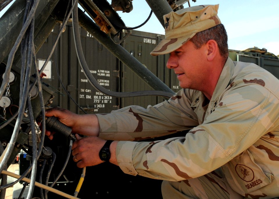 US Navy 090217-N-1120L-005 Information Systems Technician 1st Class Alan Decker, assigned to Naval Mobile Construction Battalion (NMCB) 7, inserts a cord into the transmitter dish of a Ruggedized Deployable Satellite Communicat