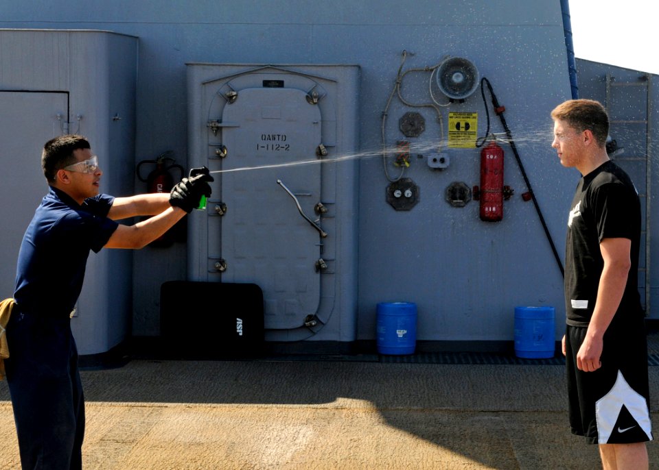 US Navy 090213-N-7280V-009 Storekeeper Seaman Sergio Torres sprays Seaman Chad Tomes with lemon juice to simulate getting spayed with Oleoresin Capsicum