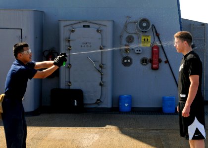 US Navy 090213-N-7280V-009 Storekeeper Seaman Sergio Torres sprays Seaman Chad Tomes with lemon juice to simulate getting spayed with Oleoresin Capsicum