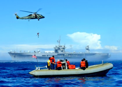 US Navy 090218-N-3830J-492 Members of the amphibious command ship USS Blue Ridge (LCC 19) search and rescue boat crew look on as a search and rescue swimmer is lifted from the ocean during a training exercise