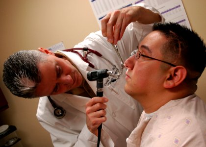 US Navy 090217-N-6326B-002 Cmdr. Craig Salt, department head of plastic surgery at Naval Medical Center San Diego, examines the nasal cavity of Lance Cpl. Anthony Guererro