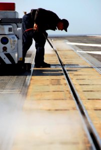 US Navy 090219-N-9760Z-017 Aviation Boatswain's Mate (Equipment) Airman Aaron Patterson pressure washes catapult number four aboard USS Nimitz (CVN 68) photo