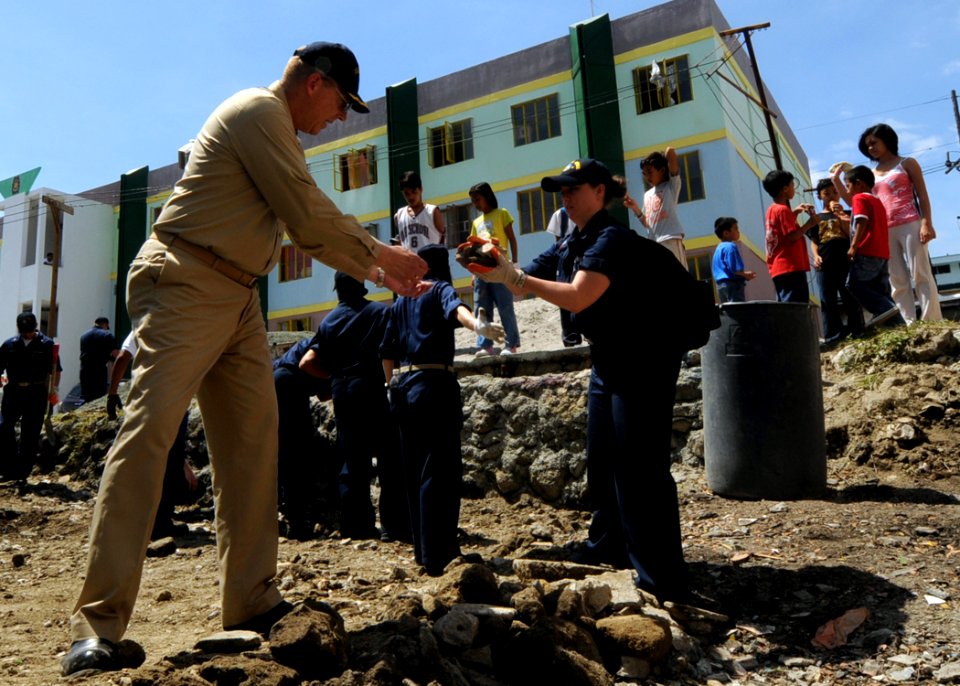 US Navy 090220-N-3262C-274 Cryptologic Technician (Collection) 1st Class Nicole Duran hands off debris to Capt. James Puttler, U.S. 7th Fleet chaplain, while clearing a lot for the construction of a playground