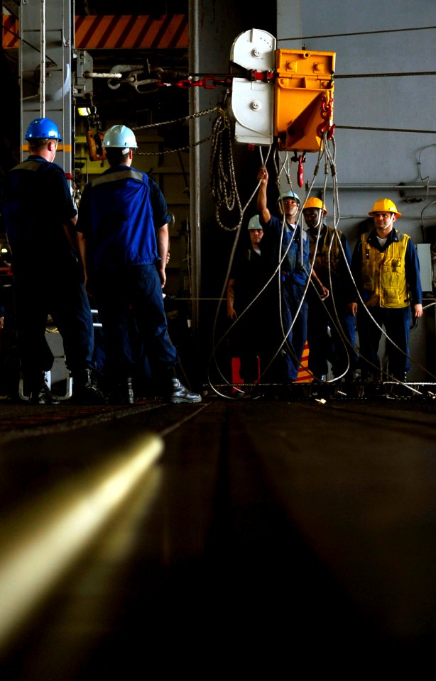 US Navy 090223-N-9928E-099 Sailors prepare to raise a sliding pad-eye after removing stores in the hangar bay aboard USS John C. Stennis (CVN 74)