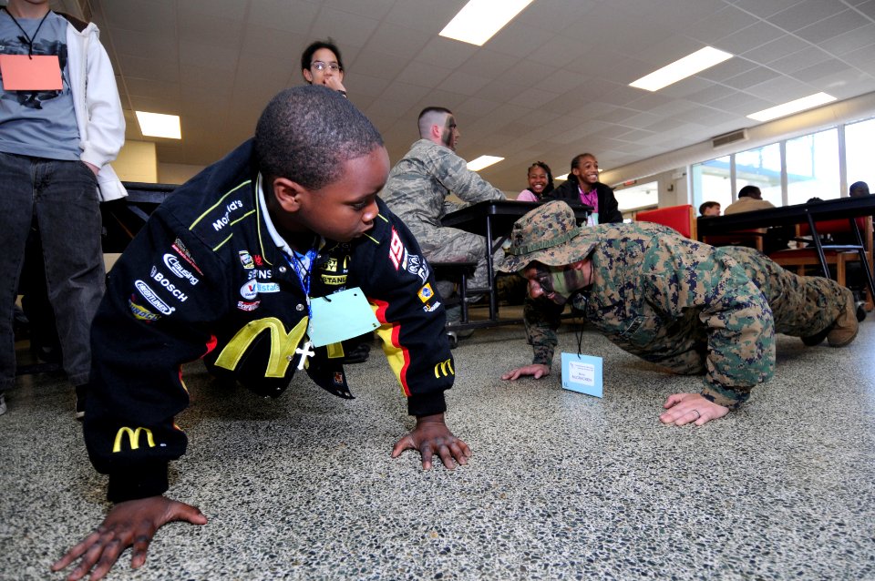 US Navy 090221-N-5328N-119 A West Pensacola Elementary School Saturday Scholar student, who says he wants to become a Marine, does push ups with Saturday Scholar mentor Pfc. Kayla McCracken, from Longview, Texas photo