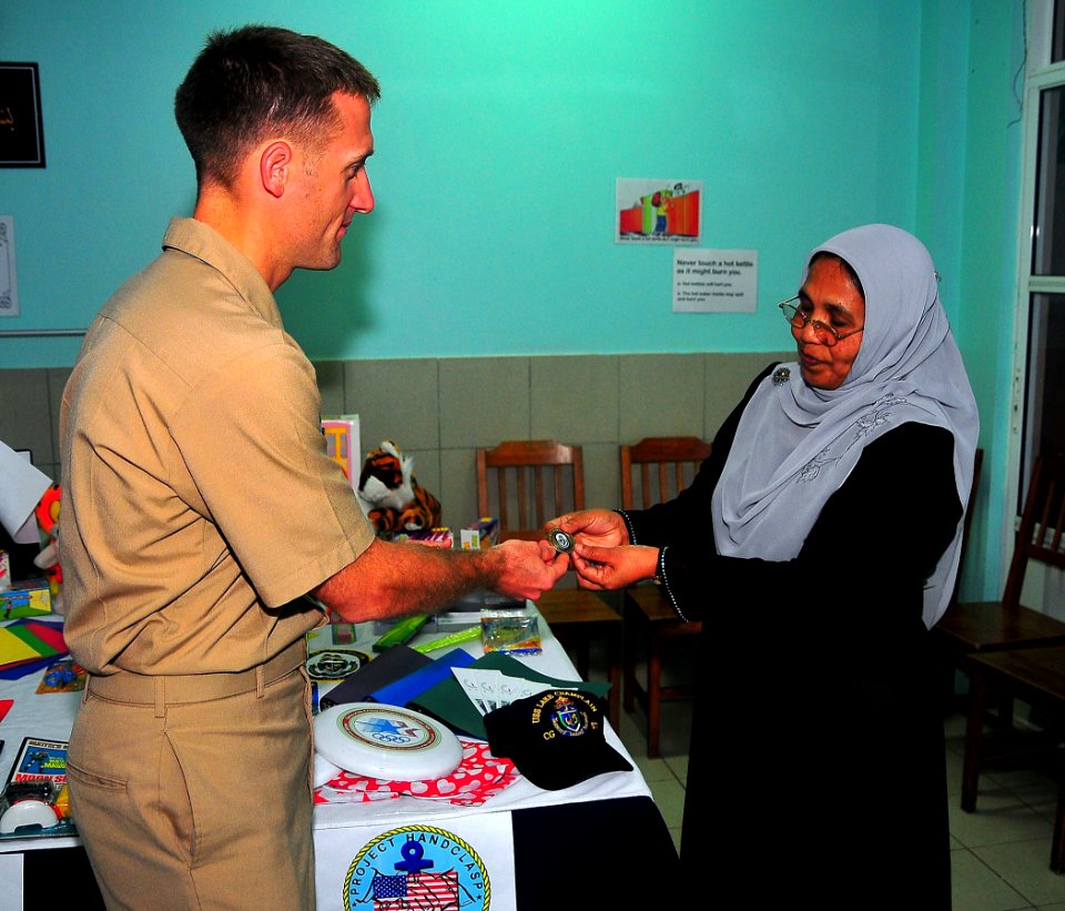 US Navy 090220-N-4774B-046 Lt. j.g. Jarrod Johnson hands a ship's coin to the head of staff of the Kuda Kudhin ge Hiya neglected children's home in Villingili