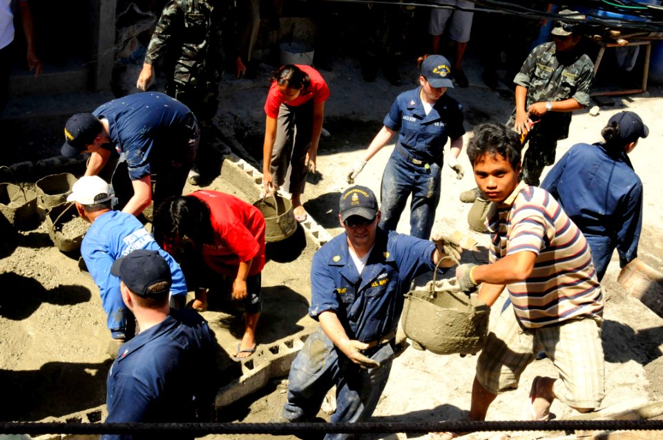 US Navy 090221-N-8546L-037 A Filipino man passes Chief Information Systems Technician Jeffrey Bryant, U.S. 7th Fleet staff, an empty bucket