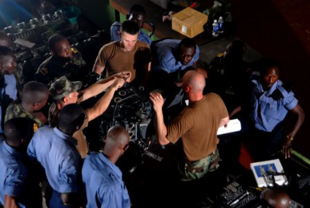 US Navy 090226-N-1688B-061 hief Engineman Edward Young, Equipment Operator 1st Class Thomas Bonacci and Hull Technician 2nd Class Thomas Wojcinski train Ghanaian and Mozambiquen sailors to fix small boat out board engines photo