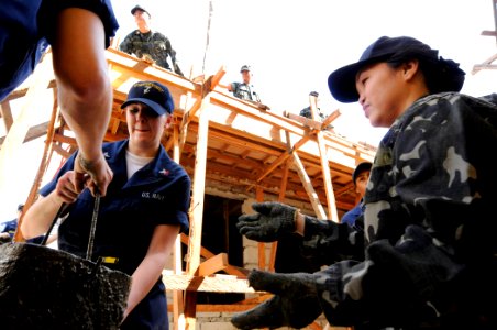 US Navy 090221-N-8546L-392 ntelligence Specialist 2nd Class Jessica Helms, assigned to the U.S. 7th Fleet staff embarked aboard the amphibious command ship USS Blue Ridge (LCC 19), passes a bucket of concrete to a sailor from t