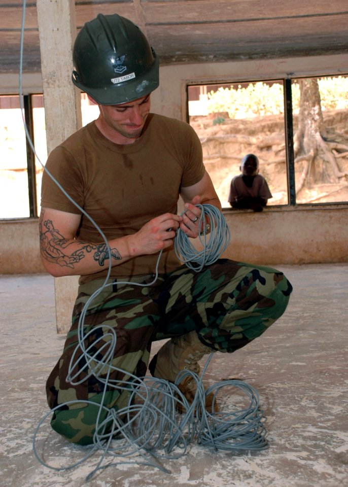 US Navy 090302-N-1655H-397 Utilitiesman 2nd Class Jospeh Tabor, assigned to Naval Mobile Construction Battalion (NMCB) 11, installs new wiring for lights during a refurbishment project at the Naval Base Basic School